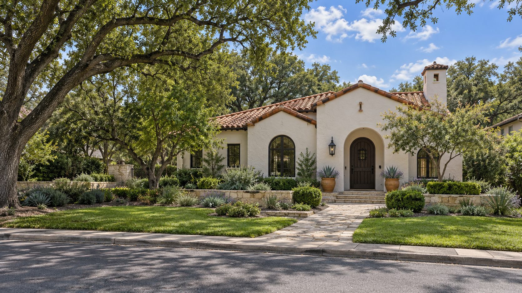 Spanish Revival stucco home with a clay tile roof and an arched wooden front door
